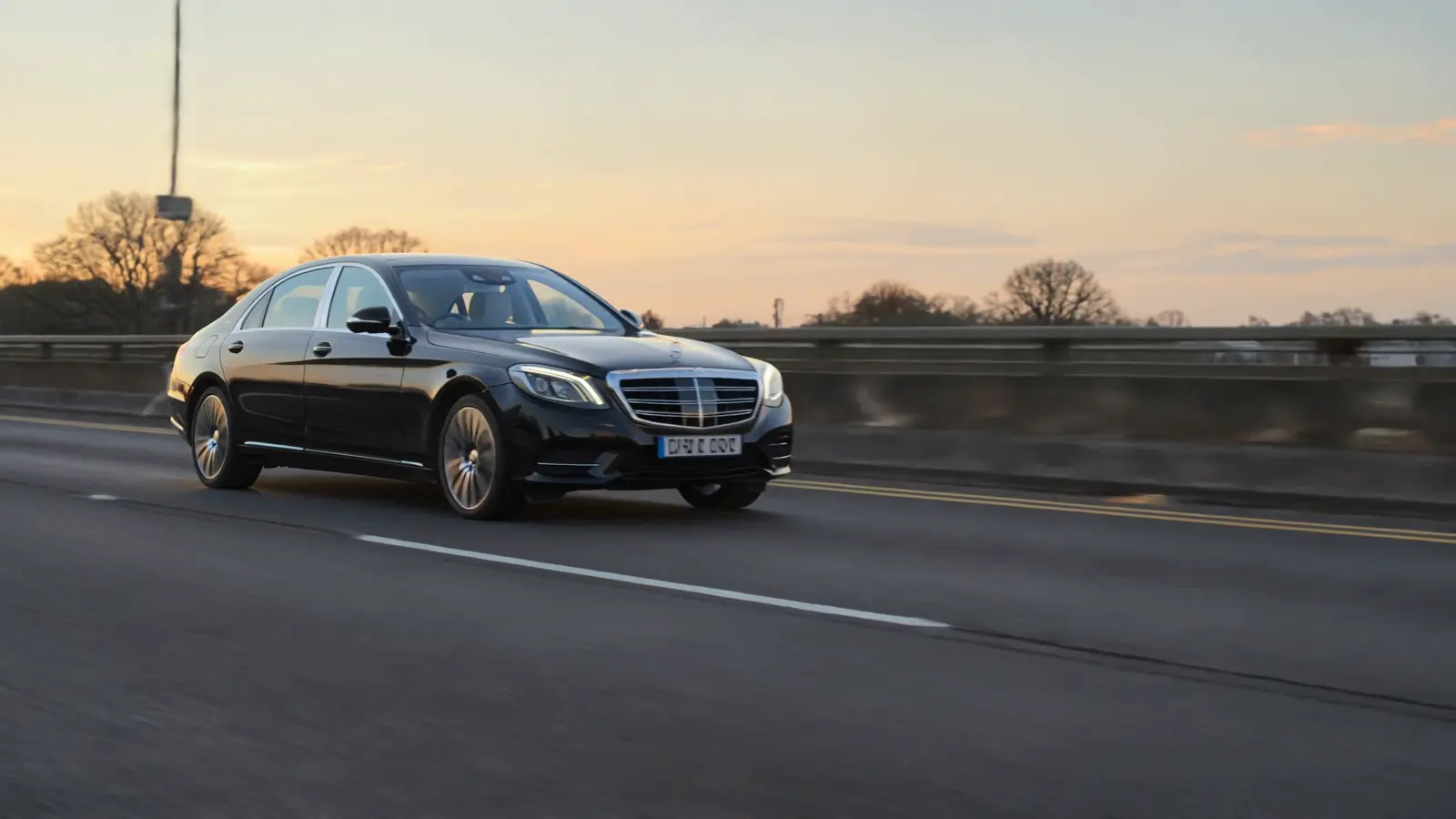A black executive saloon travelling in evening light